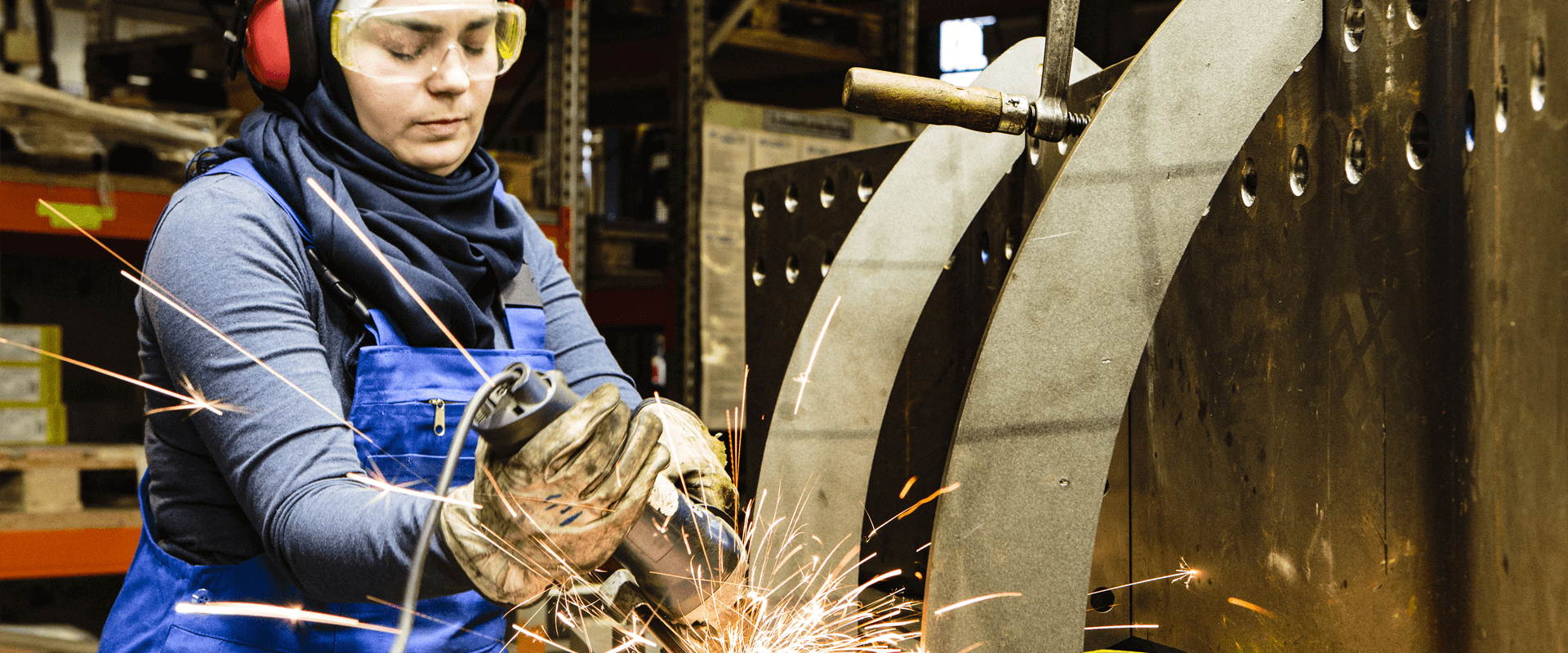 A woman welds something wearing thick safety gloves